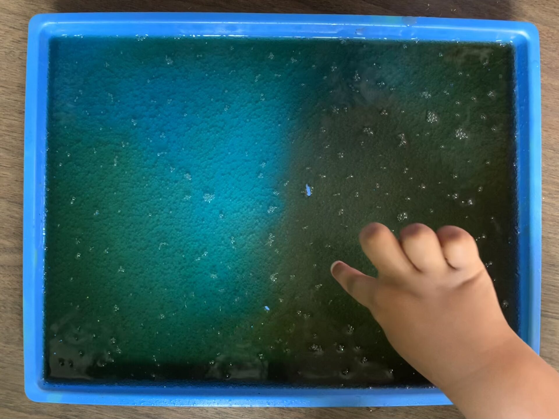 A child 's hand touching the screen of an interactive toy.